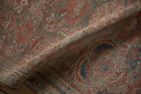 A soft fold revealing the distressed low pile and visible knot heads of the vintage rug.