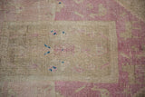 Worn knot heads on a distressed Bijar rug in pale magenta and coffee brown.