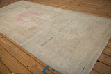 Angled view of the distressed Persian rug runner's time-softened patina and pale magenta medallion.