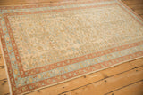 Angled perspective on a distressed Mehriban rug showing the floral field and rust and blue border.