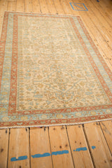 Angled view of a distressed Mehriban rug's decorative floral pattern in soft, faded colors.