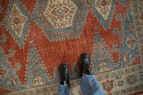 Detail of a sapphire blue and ivory medallion on the distressed cherry red field of a vintage Veece carpet.