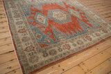 Angled view of the distressed vintage Veece carpet's cherry red and sapphire blue geometric design.