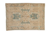 Distressed vintage Oushak rug with a geometric shield medallion in soft denim blue, sand, and coffee brown tones.