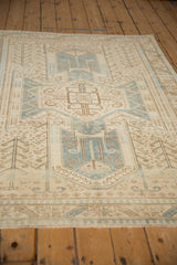 Angled view of a vintage Oushak's soft, textured pile featuring its shield medallion in blue and sand.