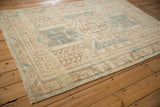 Angled perspective of a distressed Oushak rug, showing the shield medallion and pawn motif borders.