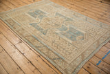 Vintage distressed Oushak rug from an angle, showcasing the denim blue and sand palette.