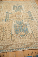 Perspective view of a distressed Oushak rug's low pile and geometric motifs in sand and denim blue.