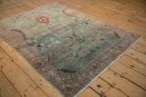 Angled view of a vintage distressed Meshed rug showing pictorial birds on a powder blue field.