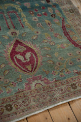 Angled detail of a vintage Persian rug's scrolling arabesque border and red palmette motif.