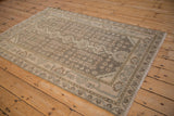 Angled view of a distressed Persian Hamadan rug with geometric floral motifs in neutral tones.