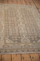Angled view of the distressed Hamadan rug's even wear and geometric patterns in silver and beige.