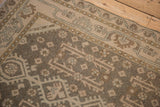Low-pile texture of a distressed Hamadan rug showing geometric floral guls in beige and brown.