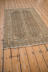 Angled view of a distressed vintage Hamadan rug highlighting its muted geometric pattern and low pile.