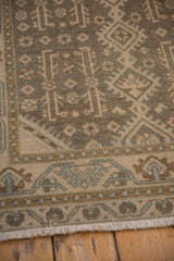 Evenly worn texture on the corner border of a distressed Hamadan rug in muted earthy tones.