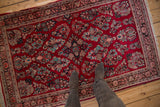 Cherry red field of vintage Sarouk rug with vibrant turquoise floral sprays and patterned border.