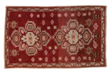 Vintage Caucasian rug with a geometric double medallion design in rust, silver, and pink tones.