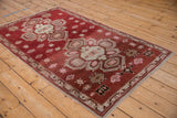Angled perspective on a vintage Caucasian rug's geometric medallion, border, and abrashed rust field.
