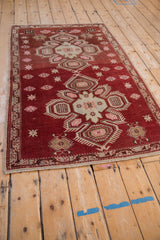 Angled view of a vintage Caucasian rug highlighting its distressed texture and geometric double medallion.