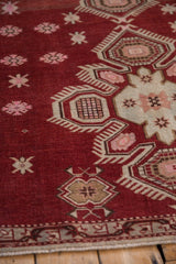 Angled detail of the vintage Caucasian rug's finned medallion and crab-style floral motifs.