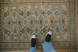 Distressed vintage Tabriz rug featuring sapphire blue geometric guls and brown pawn motif borders.