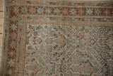 Corner of a distressed Persian Mahal rug showing the textured, low-pile and narrow border details.