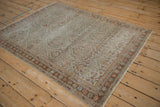 Angled view of the vintage distressed Mahal rug showing its low pile and allover trellis design.