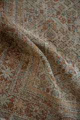 The soft, weathered pile and hand-knotted texture of a distressed Persian rug.