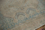 Detailed view of the distressed rug's texture, highlighting low-pile wear and geometric sky blue patterns.