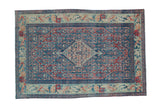 Distressed vintage Senneh rug with a concentric medallion in sapphire blue and cherry red over a Herati field pattern.