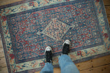 Distressed Persian Senneh rug showing scale with a bold blue, red, and ivory medallion.