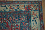 Detailed floral border contrasts with the sapphire blue Herati field on a worn Persian rug corner.