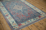 Angled view of a distressed Senneh rug's shield-like medallion and time-softened colors.