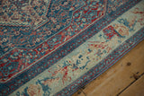 Corner view of a vintage Senneh rug showing its worn floral bouquet border and Herati pattern.
