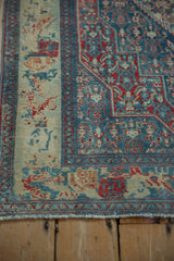 Detailed floral border and blue Herati field on the corner of a distressed vintage Senneh rug.