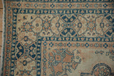 Vintage distressed Tabriz rug corner with dusty sapphire and pale terracotta border designs.