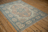Distressed vintage Tabriz rug with dusty sapphire border and scalloped terracotta floral vines.