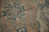 Distressed vintage Tabriz rug with terracotta, dusty blue floral vines, and visible knot heads.
