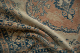 Distressed vintage Tabriz rug detail showing sapphire blue floral vines on terracotta and sand.
