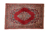 Vintage Sarouk rug with a central diamond medallion and dense floral sprays on a cherry red field.