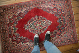 Overhead view of the vintage Sarouk rug's central diamond medallion on a cherry red field.