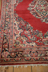 Angled view of a vintage Sarouk rug's floral spandrel and intricate multi-layered border.