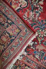 Intact red side cord, fringe, and traditional floral border of a vintage Persian Sarouk rug.