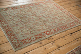 Angled view of a vintage Senneh rug's distressed Herati design in dusty teal and rust.