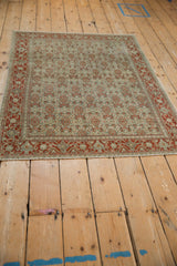 Angled view of a distressed Persian Senneh rug with a traditional allover Herati design.