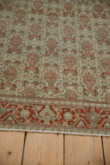 Angled view of a distressed rug's worn pile, showing the rust and dusty teal turtle samovar motifs.