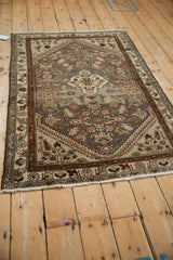 Distressed corner of vintage Hamadan rug, with short fringe, time-softened tones, and Herati motif.