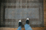 In-situ view of a vintage distressed Belouch rug, showcasing its even wear and soft blue tones.