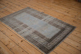 Angled view of a vintage Belouch rug showing its abrashed blue field and tiered borders.