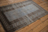 Perspective view of a distressed Belouch rug with dusty blue and charcoal brown tones.